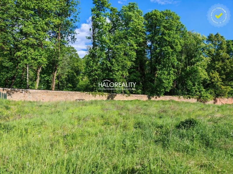 Lands - housing in Spišský Hrhov, grassy area surrounded by trees and a stone wall.