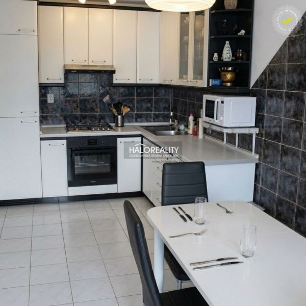 A kitchen with white cabinets in a 3-room apartment, a dining table, and ceramic tiles.