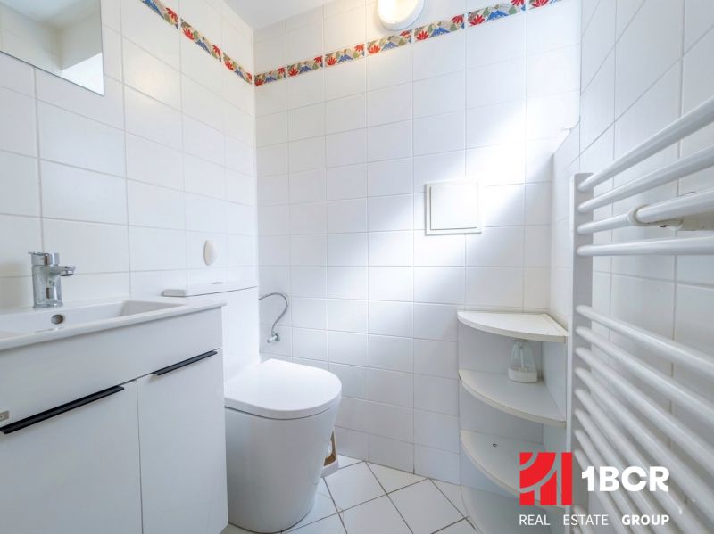 Bathroom with a shower and white tiles in a 2-room apartment.