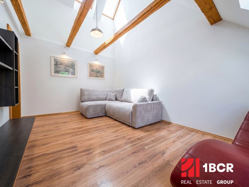 A bright living room with wood-patterned flooring and a comfortable sofa in a two-room apartment.