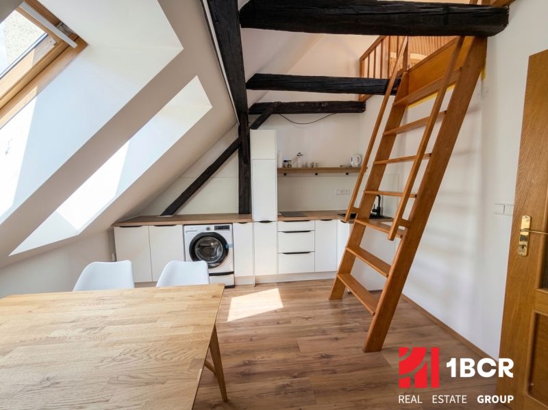 A kitchen in a 2-room apartment with skylights, a staircase, and a wooden decor floor.