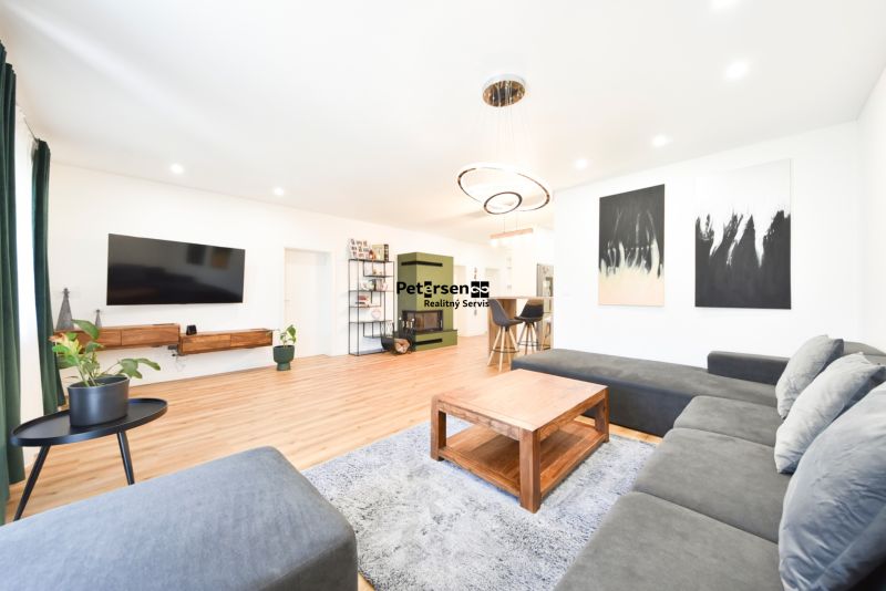Living room in a family house with a large sofa, television, and wooden decor flooring.