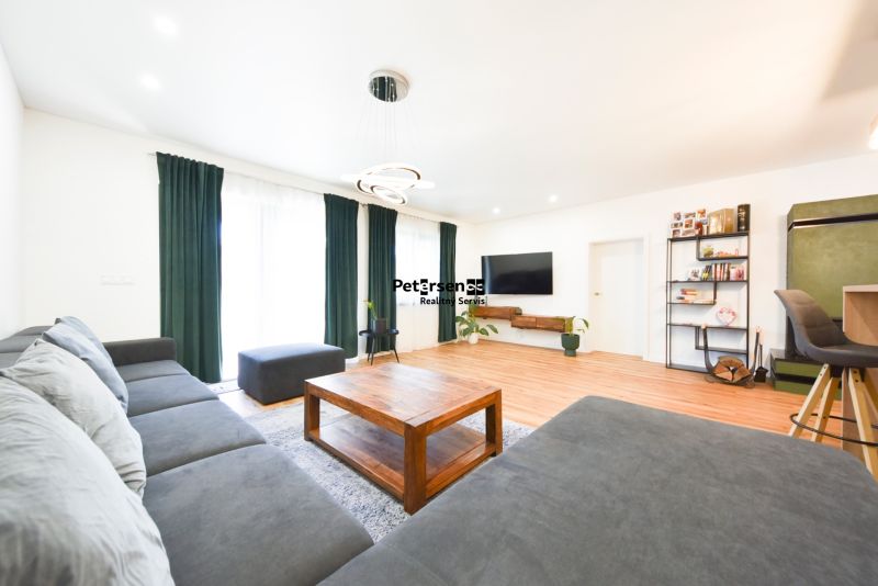 Living room with a large corner sofa and a wooden decor floor in a family house.
