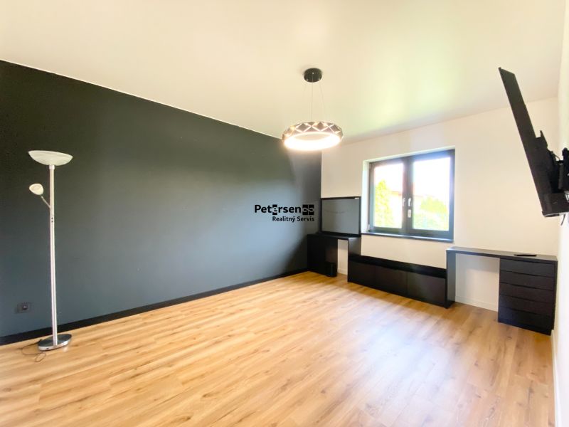 In the family house, there is a spacious room with a black wall and a floor with a wooden decor.