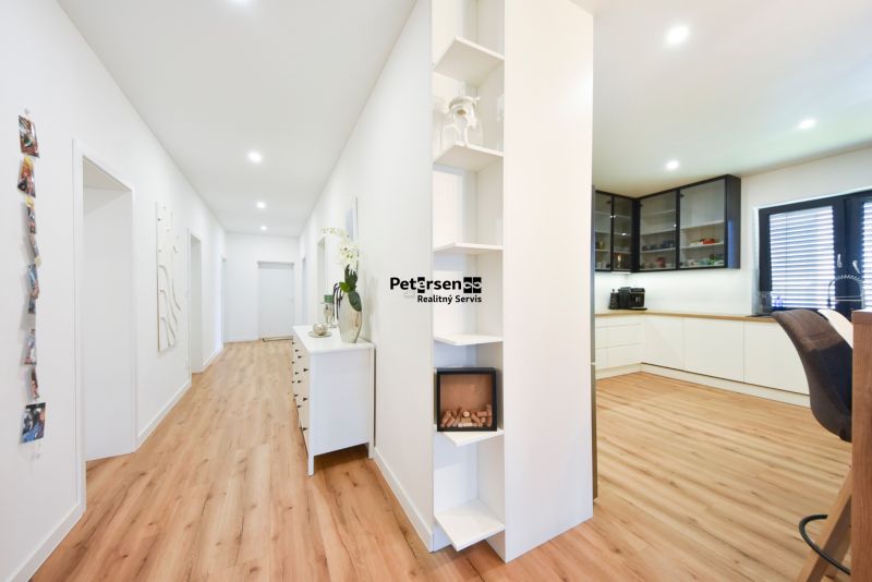 A kitchen in a family house with a wooden decor floor and white furniture.