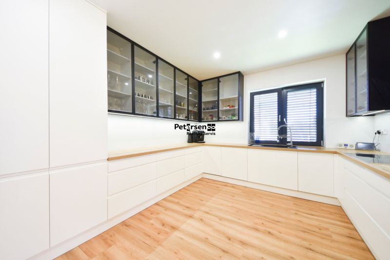 A kitchen in a family house with white cabinets and a wood-patterned floor.