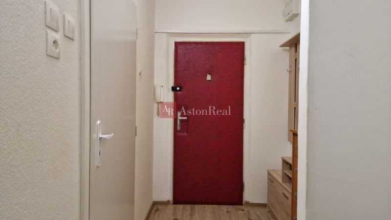The entrance hall of a 2-room apartment with a wooden decor floor and red doors.