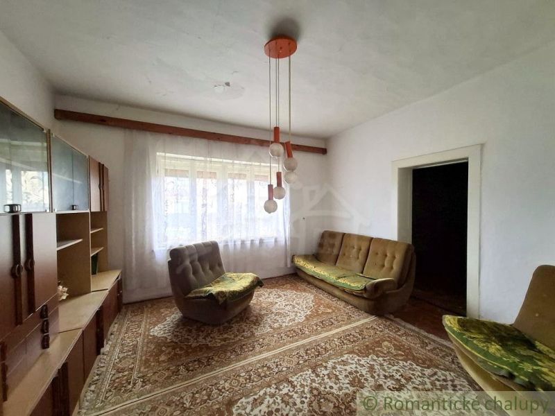 A living room in a cottage with older furniture and lighting, carpeted floor.
