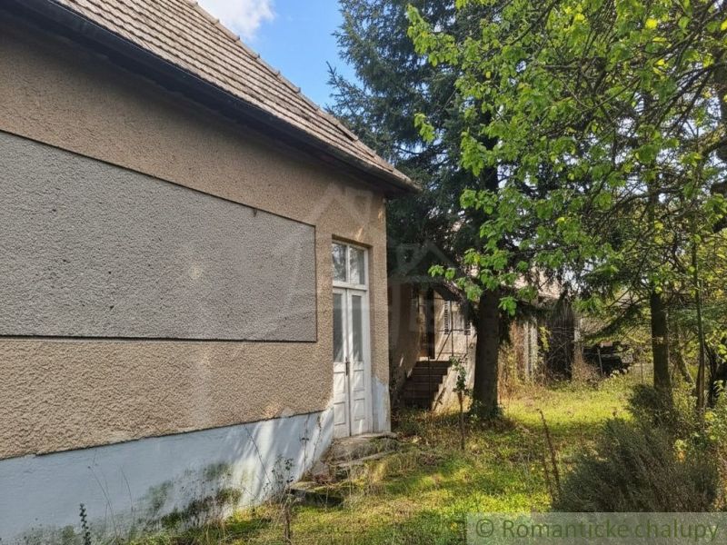 A cottage in Divín with a stone foundation and surrounded by greenery in a peaceful environment.