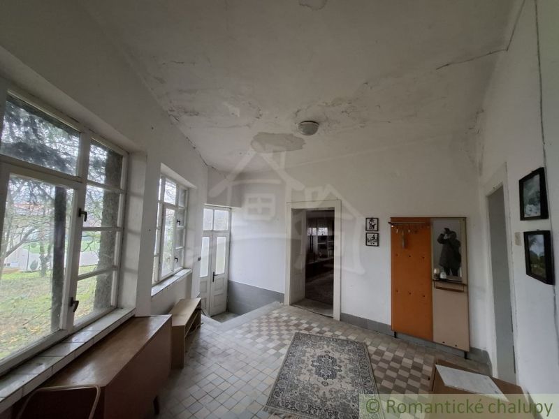 The interior of the cottage with carpet and tiles, wooden furniture, and large windows.