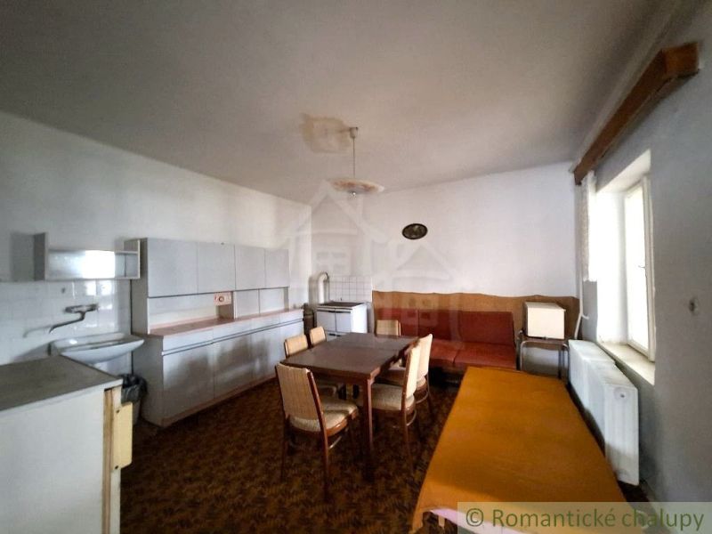 A kitchen in a cottage with furniture, a dining table, and a sofa.