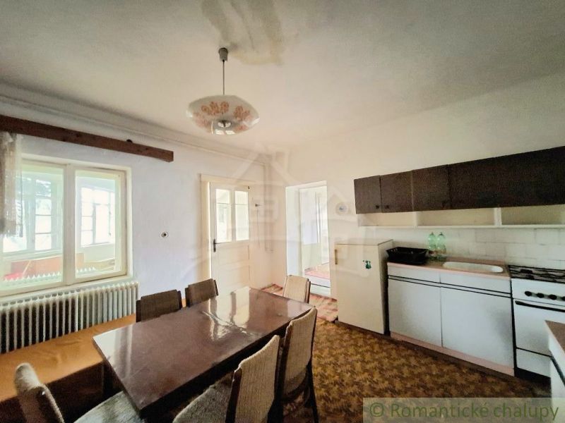 The interior of a cabin with a table, chairs, a stove, and a dining nook.