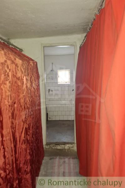 A narrow hallway with curtains leading to the bathroom in the cottage.