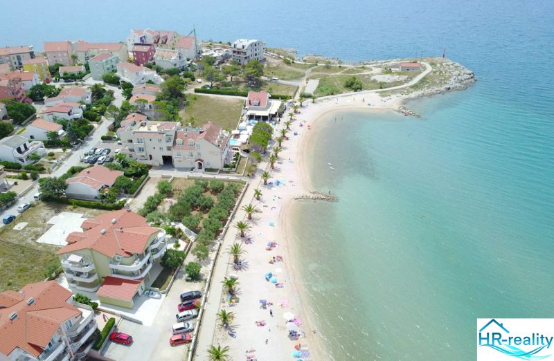 A view of the coastal area of Povljana with the beach and surrounding buildings.
