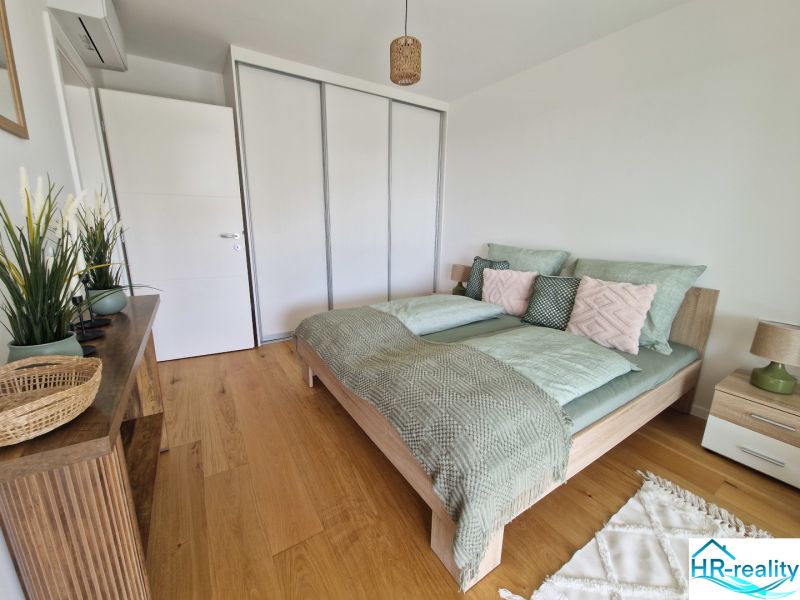 A bedroom with wood-patterned flooring in a 3-room apartment, decorated with green accessories.