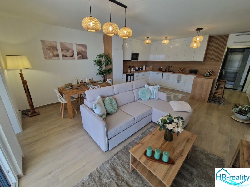 Living room of a 3-room apartment with a wooden decor floor, dining table, and sofa.