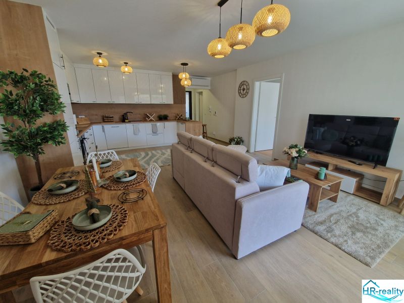 3-bedroom apartment with a kitchen, dining table, and wooden decor flooring.