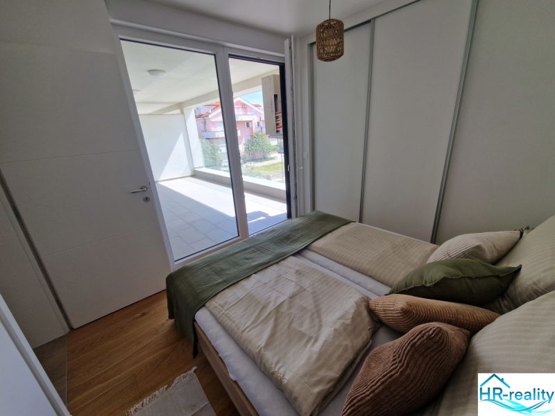 Bedroom in a 3-room apartment with wood-patterned flooring and access to the terrace.