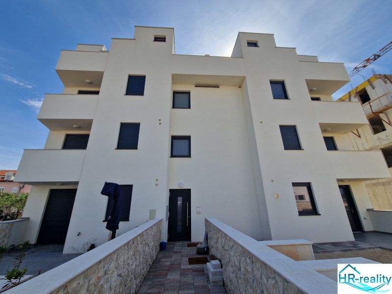 The exterior of a building with a 3-room apartment in Povljana with sunny weather.