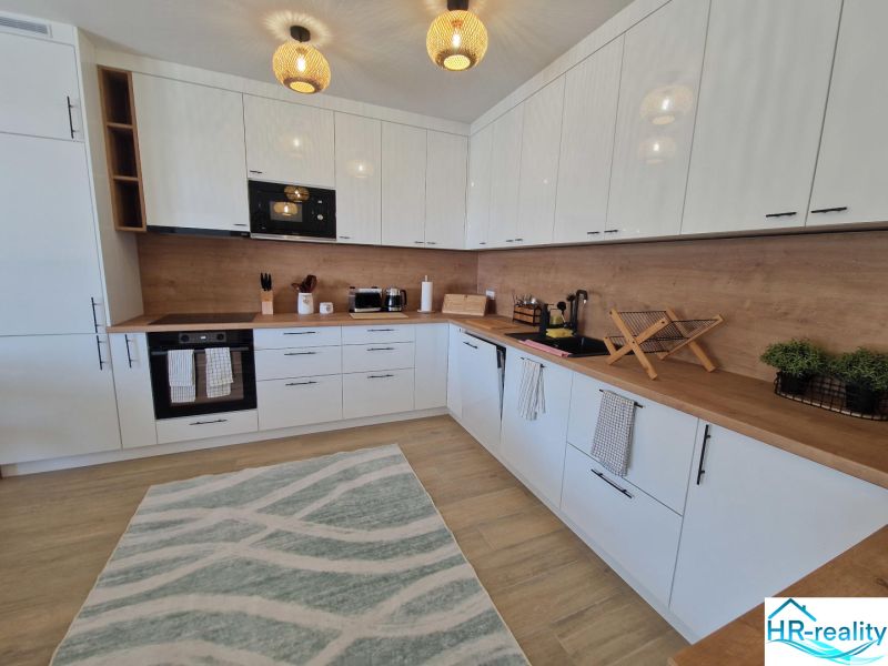 A modern kitchen in a 3-room apartment with light furniture and a wooden decor floor.