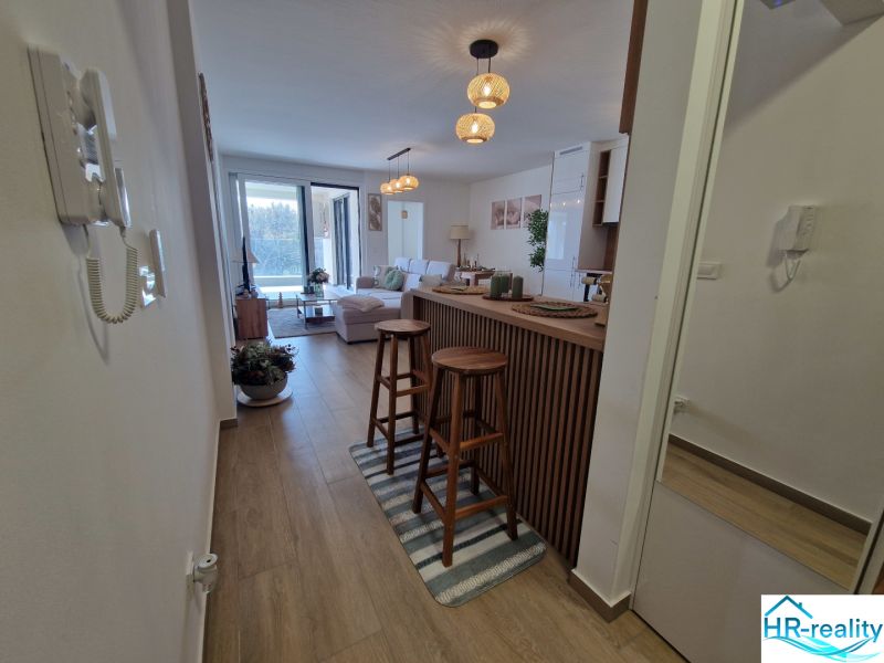 A bright living room with wood-patterned flooring and a bar counter in a 3-room apartment.