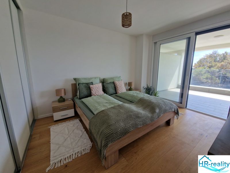 A bedroom in light tones with a wood-patterned floor in a 3-room apartment.