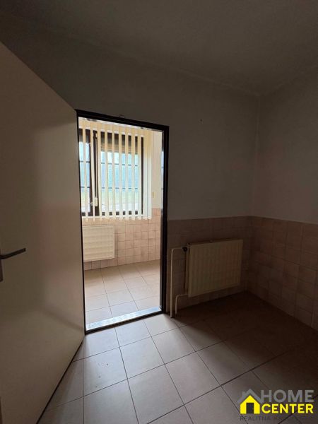 Interior commercial spaces with tiles and a radiator, light passes through vertical blinds.