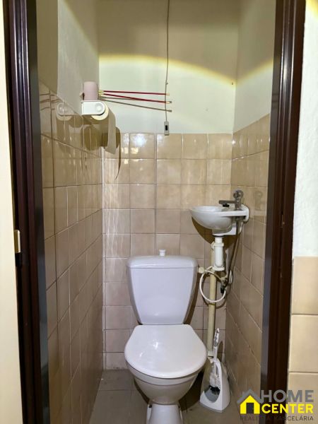 A toilet with a sink, tiled with light tiles in commercial premises.