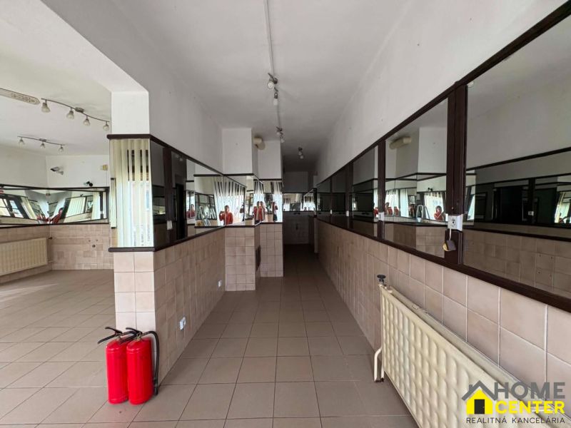 Commercial premises with tiled flooring and a mirrored wall, fire extinguishers, built-in lighting.