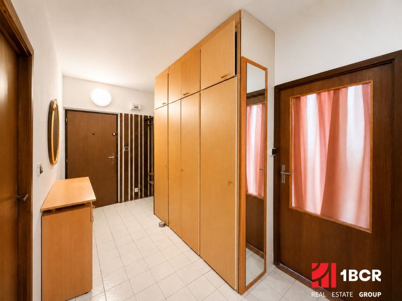 Entrance hall in a 3-room apartment with wooden doors and wardrobes, tiled floor.