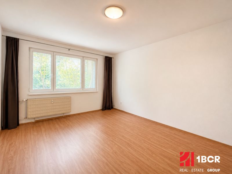 A spacious room with a wooden decor floor in a 3-room apartment.