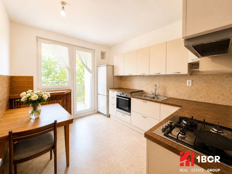 A kitchen in a 3-room apartment with a gas stove and a wooden table.