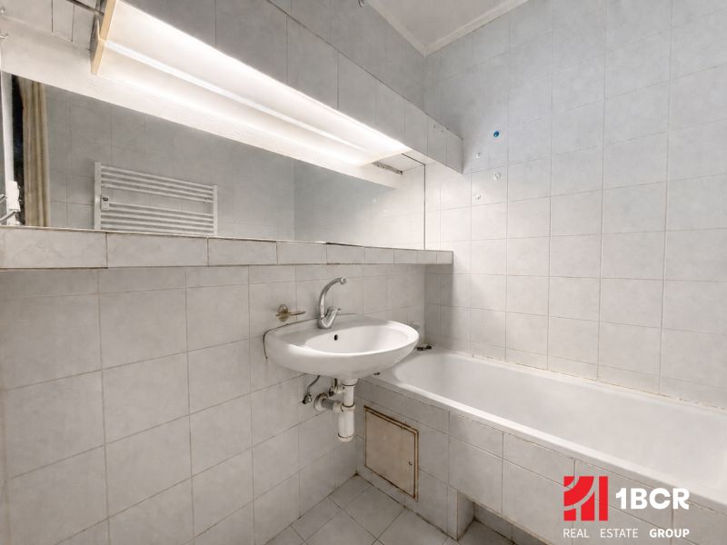 Bathroom in a 3-room apartment with a bathtub and a sink, white tiles.