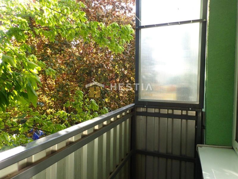 The balcony of a one-room apartment in Senica with a view of the green leaves of the trees.