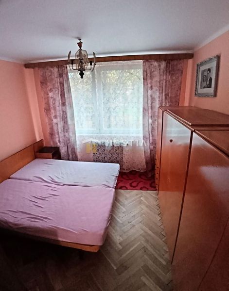 Bedroom in a 3-room apartment with a bed, wardrobe, and wooden decor flooring.