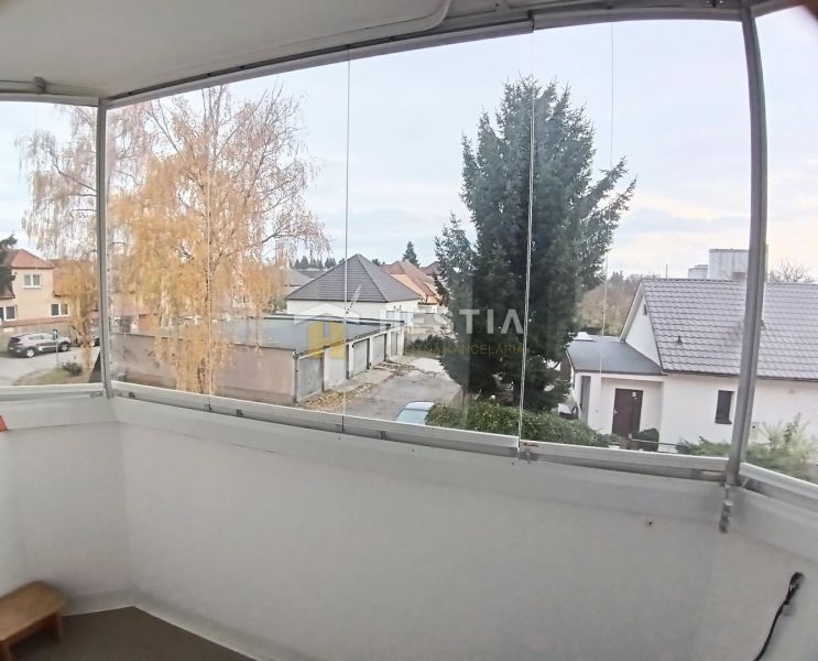 Enclosed balcony of a 3-room apartment in Senica with a view of gardens and rooftops.