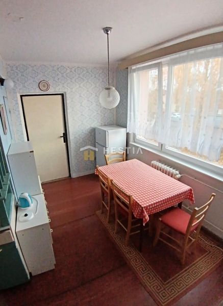 Dining nook with a window, patterned wallpaper, wood-patterned flooring, and a checkered tablecloth.