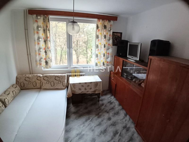 Living room in a three-room apartment with a sofa and a wardrobe, floor with a wooden decor.