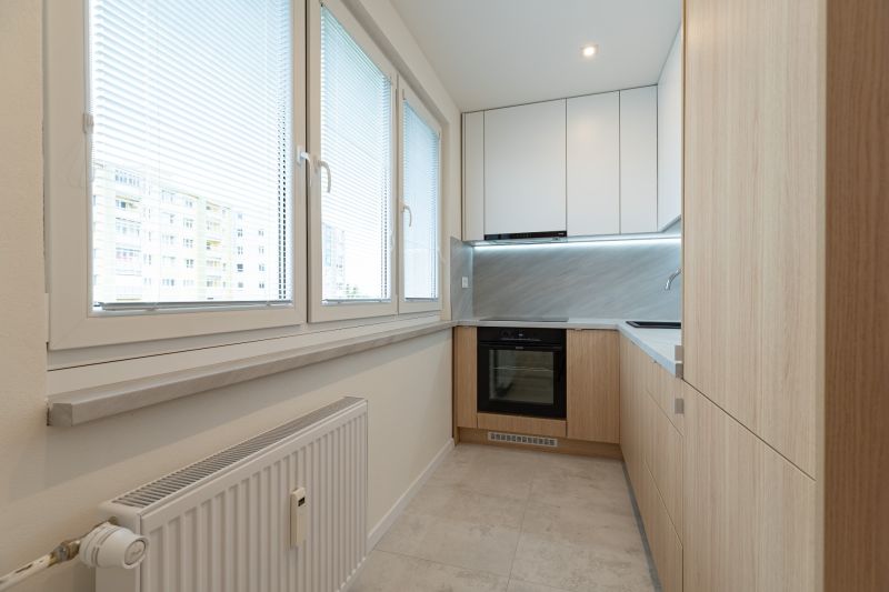 The kitchen of a 4-room apartment with a kitchen unit and large windows with blinds.