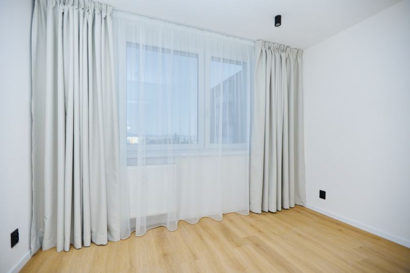 A room in a 4-room apartment with a wooden decor floor, curtains, and drapes.