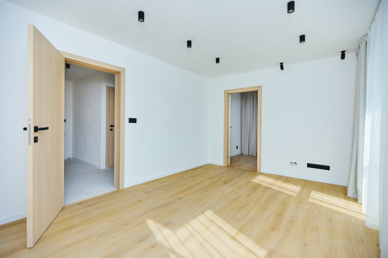 A room with a wooden decor floor and white walls in a 4-room apartment.