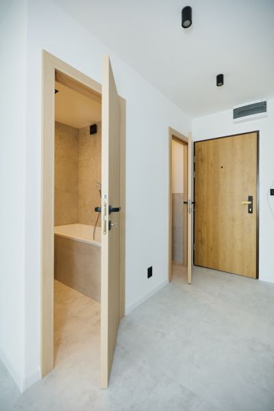 The hallway of a 4-room apartment with white walls, doors, and a bathroom.