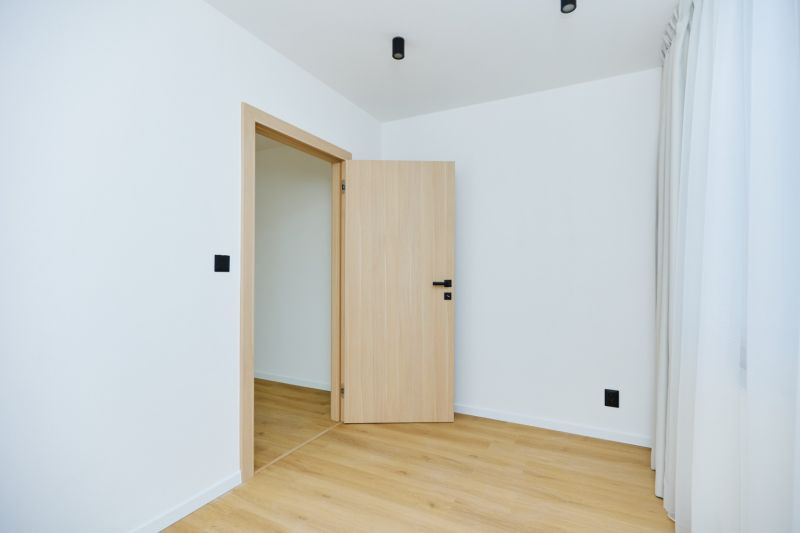 Interior of a 4-room apartment with white walls and a floor with a wood decor.