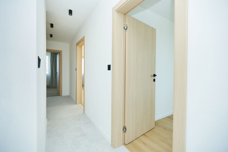 A bright hallway interior with light doors and a wooden decor floor in a 4-room apartment.