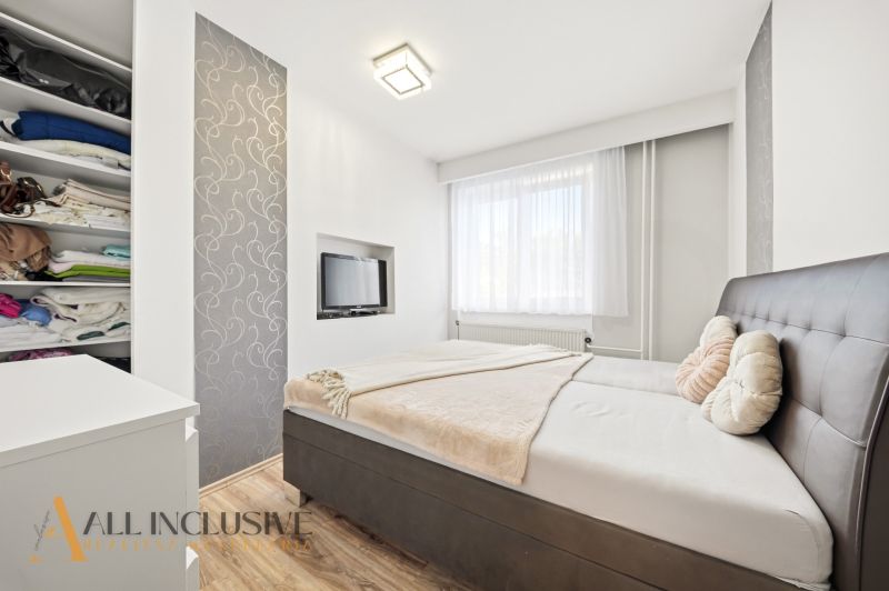 Bedroom in a family house with a bed, television, and wardrobe, floor with wooden decor.
