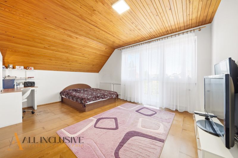 Bedroom in a family house with wooden floor decor, bed, and work desk.