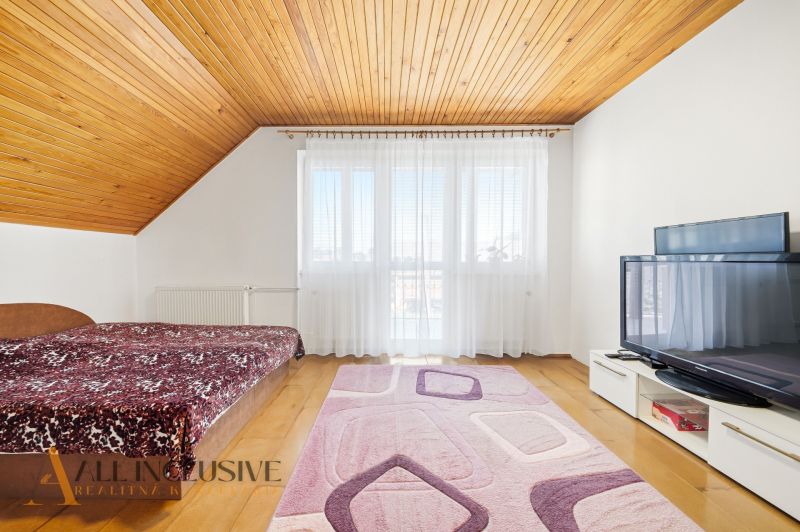 Bedroom in a family house with a wooden ceiling, floor with wooden decor, television.