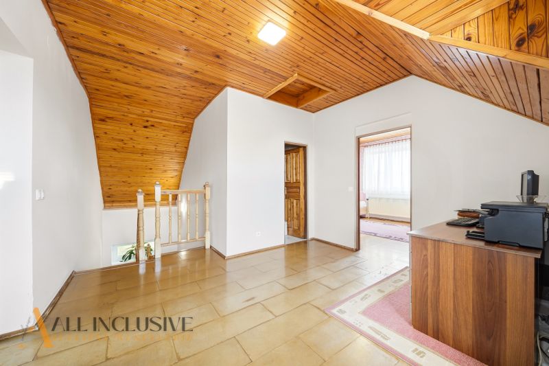 Attic space in a family house with wooden ceiling paneling and flooring with a wooden decor.