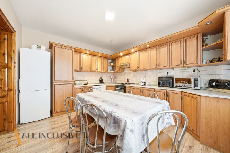 A kitchen in a family house with a kitchen unit, table, and floor with a wooden decor.