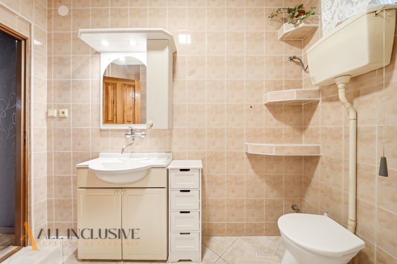 A bathroom in a family house with a white sink and mirror, light tiles.